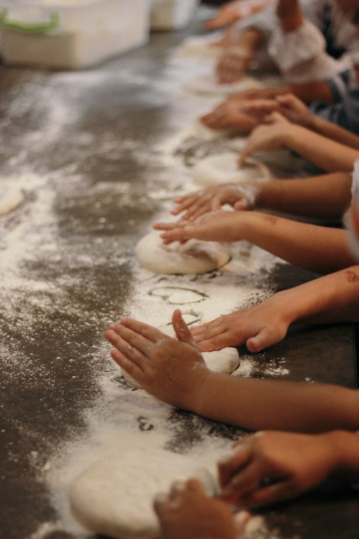 Children learning to bake by kneading dough in a hands-on workshop.