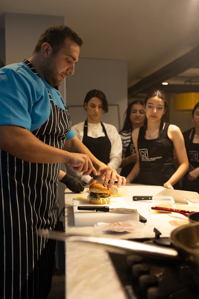 Chef preparing burgers for a cooking class in a restaurant setting.